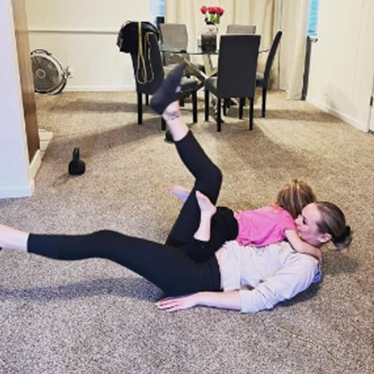 A mother and daughter have fun doing a floor workout together on the living room carpet at home in Chico, CA, showing the convenient, family-friendly way Gym Truck Chico delivers in-home personal training.