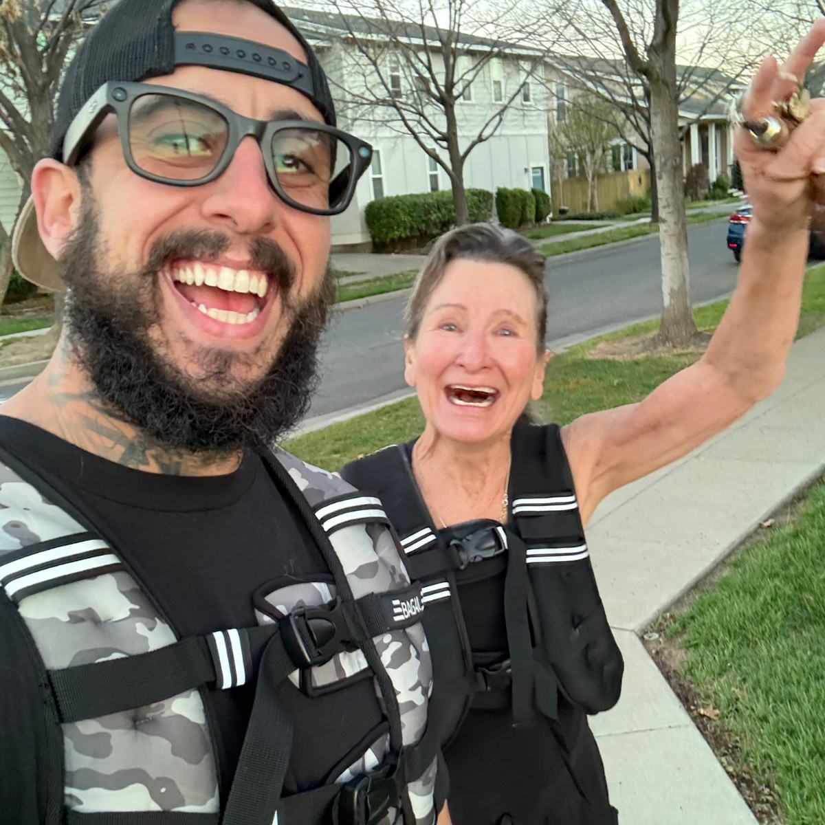 James Biccum and a client smile in weighted rucking vests on a Chico, CA neighborhood sidewalk, welcoming you to the in-home personal training experience at Gym Truck Chico.