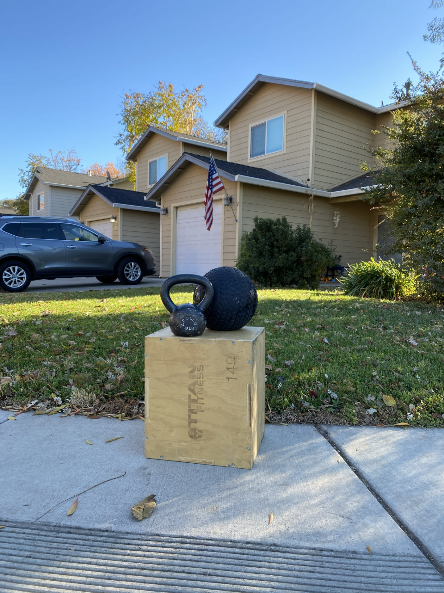 Kettlebell, slam ball, and plyo box set up on the sidewalk in front of a client's home for a mobile at-home personal training workout in Chico, CA