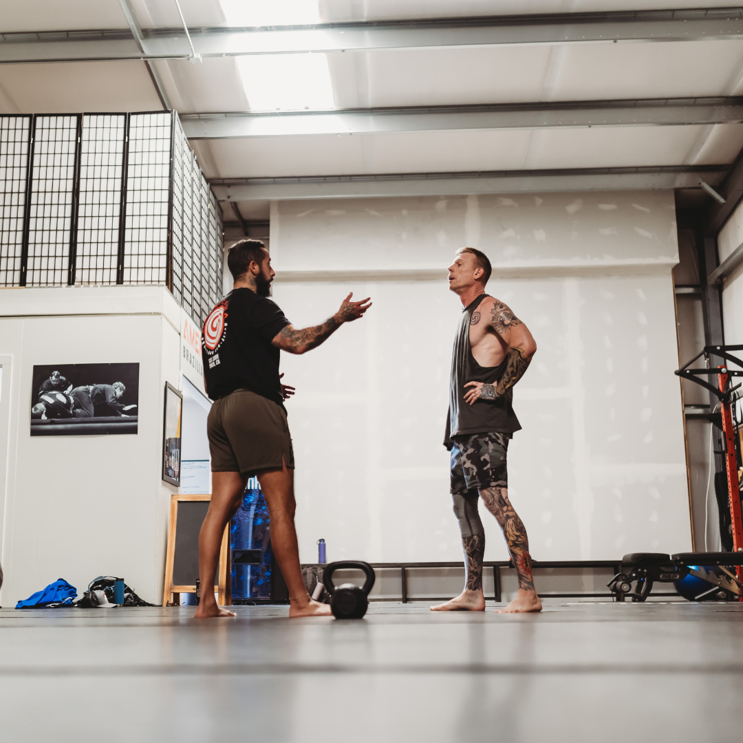 A personal trainer gives one-on-one coaching attention to a male client during a private kettlebell session, showing the fully customized personal training experience of Gym Truck Chico in Chico, CA.